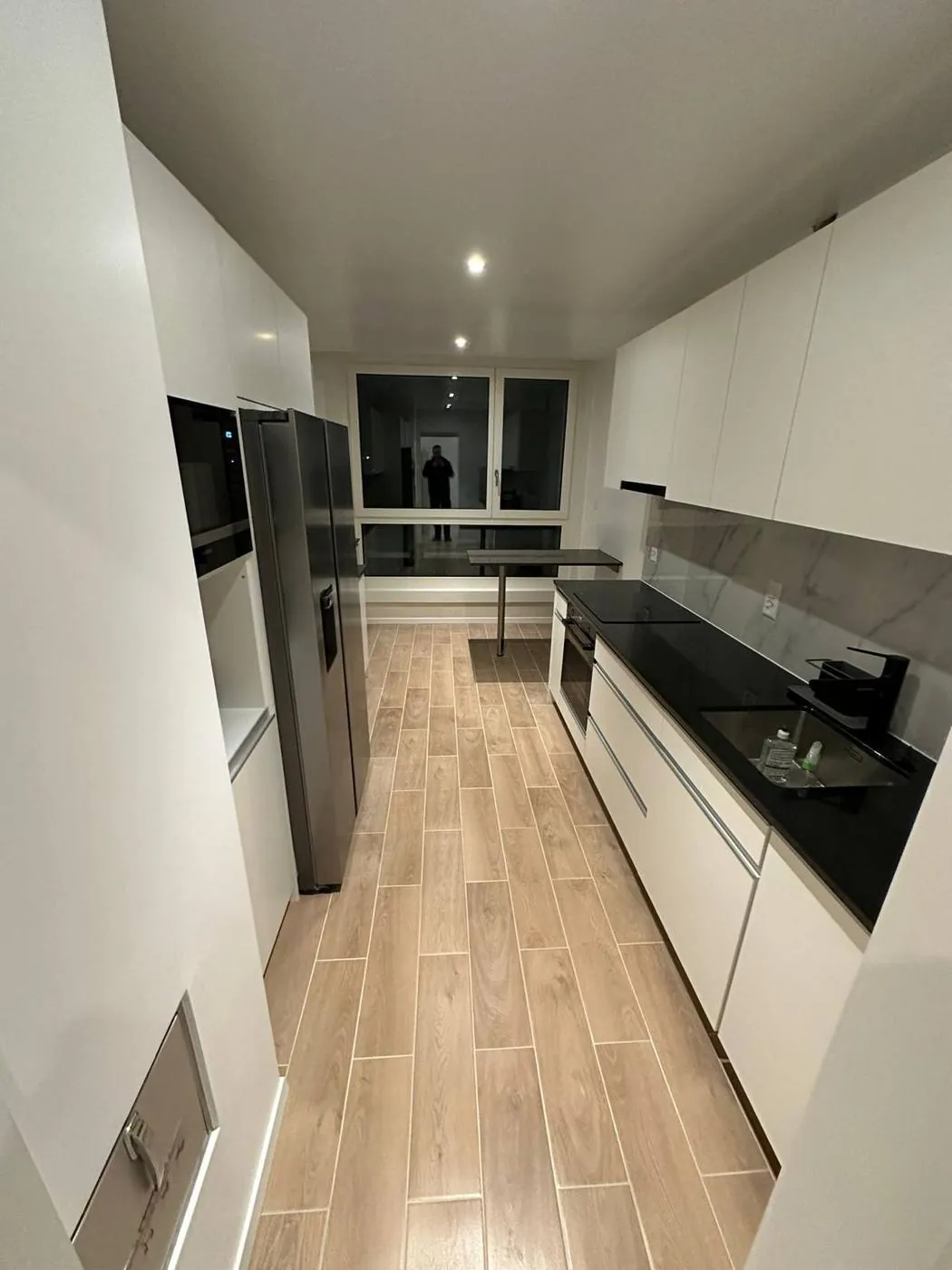 Bespoke white kitchen with black worktop and American fridge